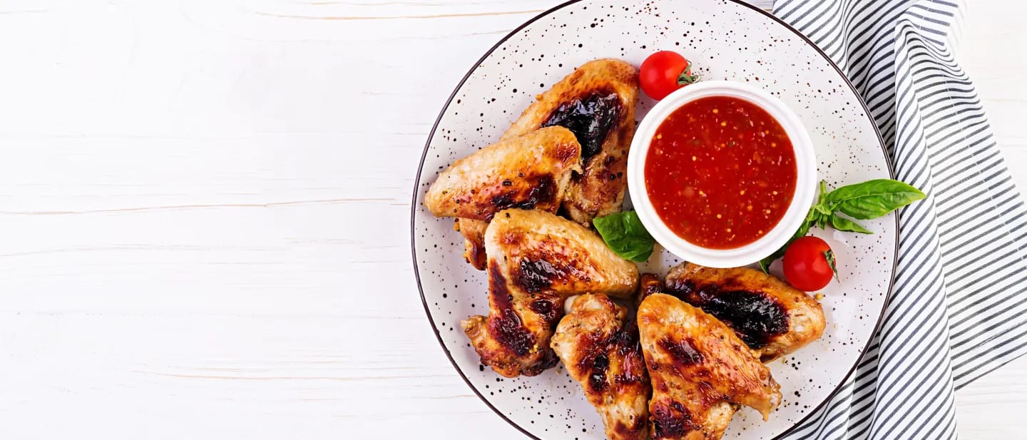 Chicken Wings on a Plate with a red Sauce on Top