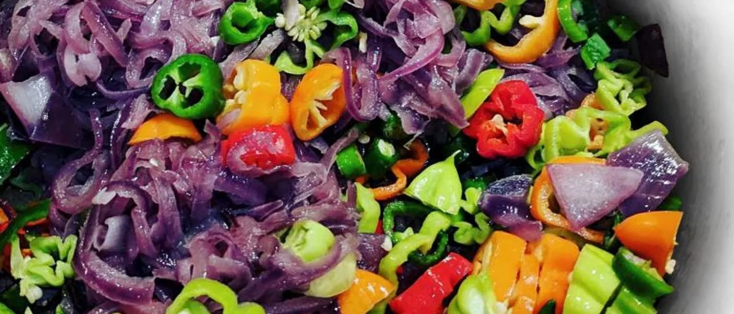 An iridescent array of chilies, onions, and garlic, slowly sweating over a low heat