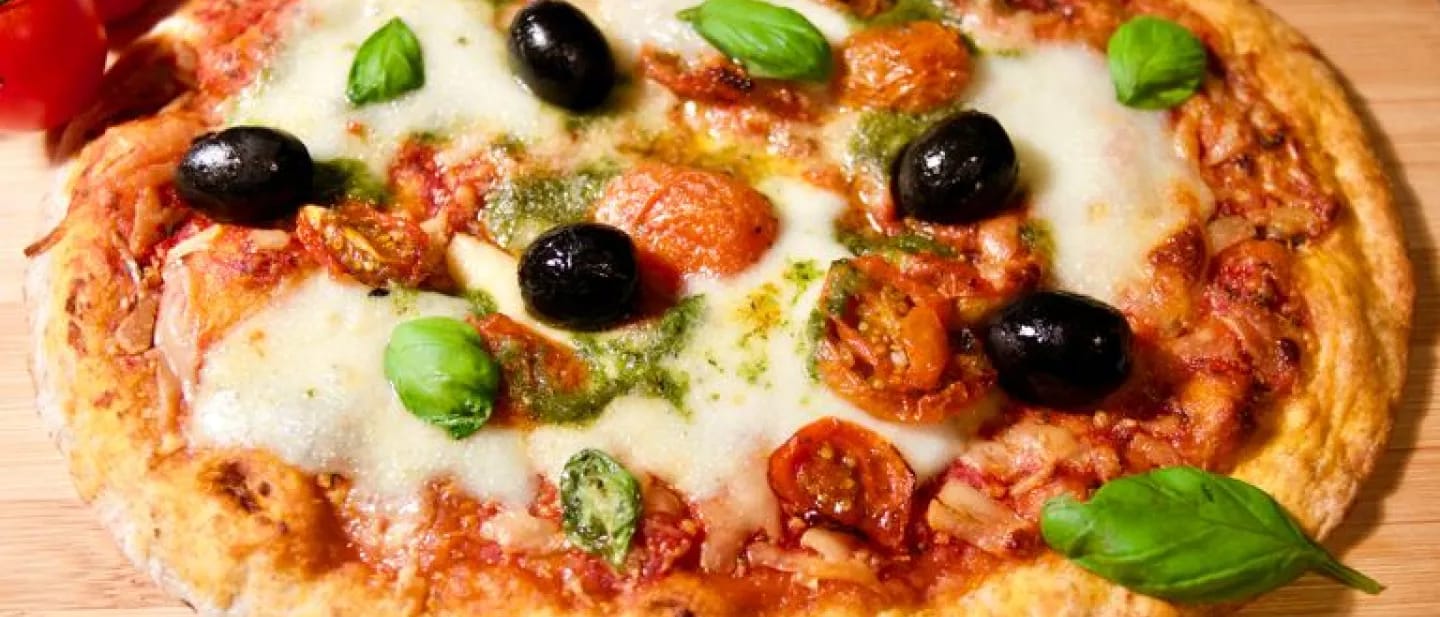 Olives, basil, and mozzarella top a gluten free pizza crust with marinara sauce