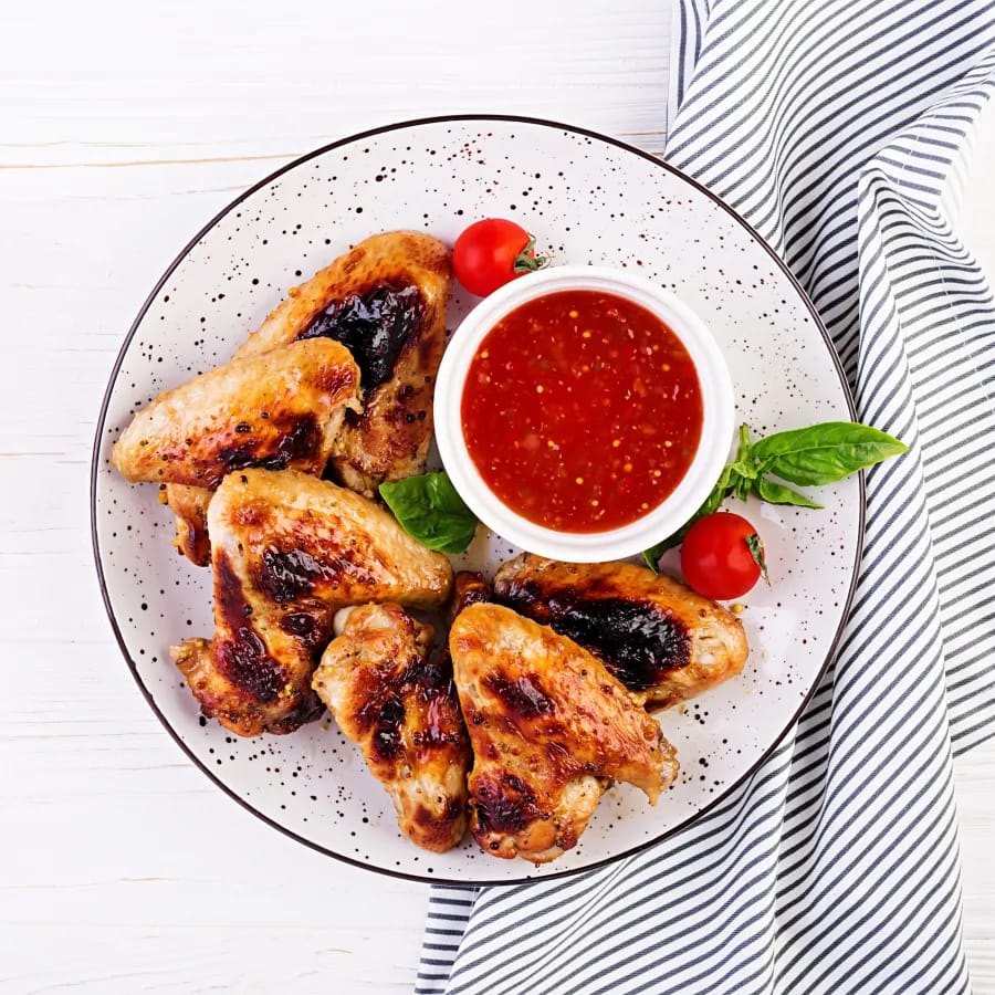 Chicken Wings on a Plate with a red Sauce on Top