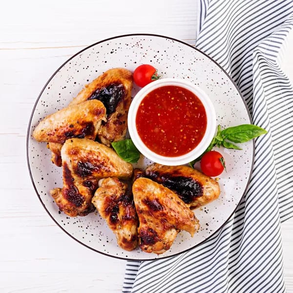 Chicken Wings on a Plate with a red Sauce on Top