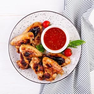 Chicken Wings on a Plate with a red Sauce on Top